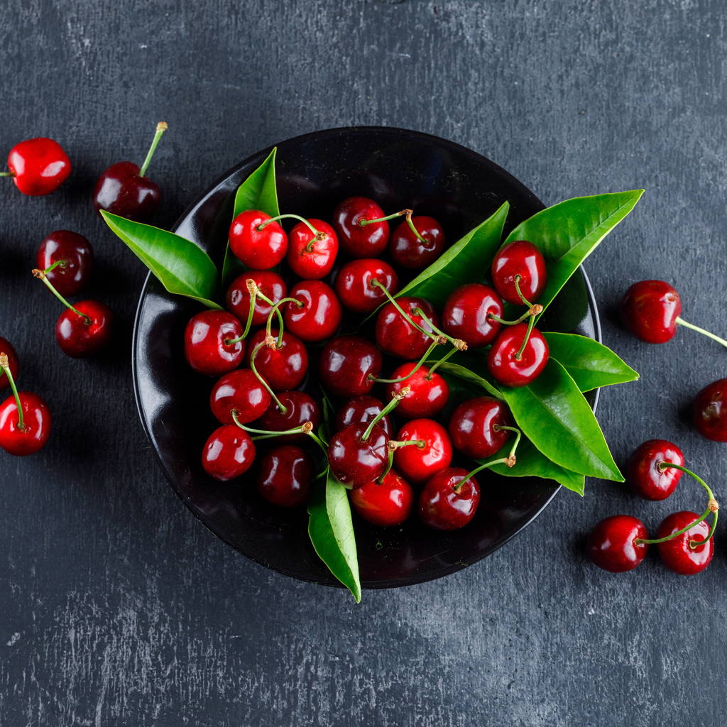 Черная  тарелка с красными ягодами черешни