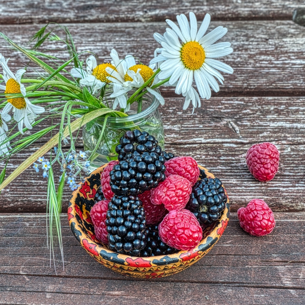 Ягоды черники и малины на столе с ромашками