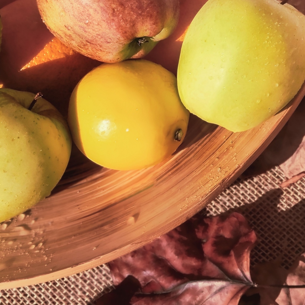 Чистые спелые яблоки на столе с шишкой