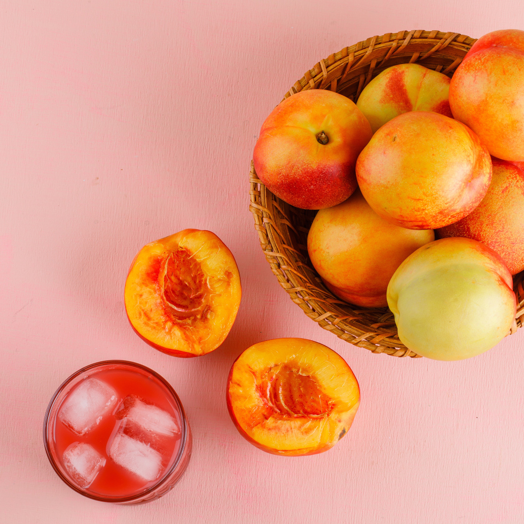 Свежий нектарин в корзине на розовом столе