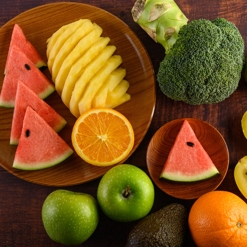 Фрукты и брокколи на столе с доской