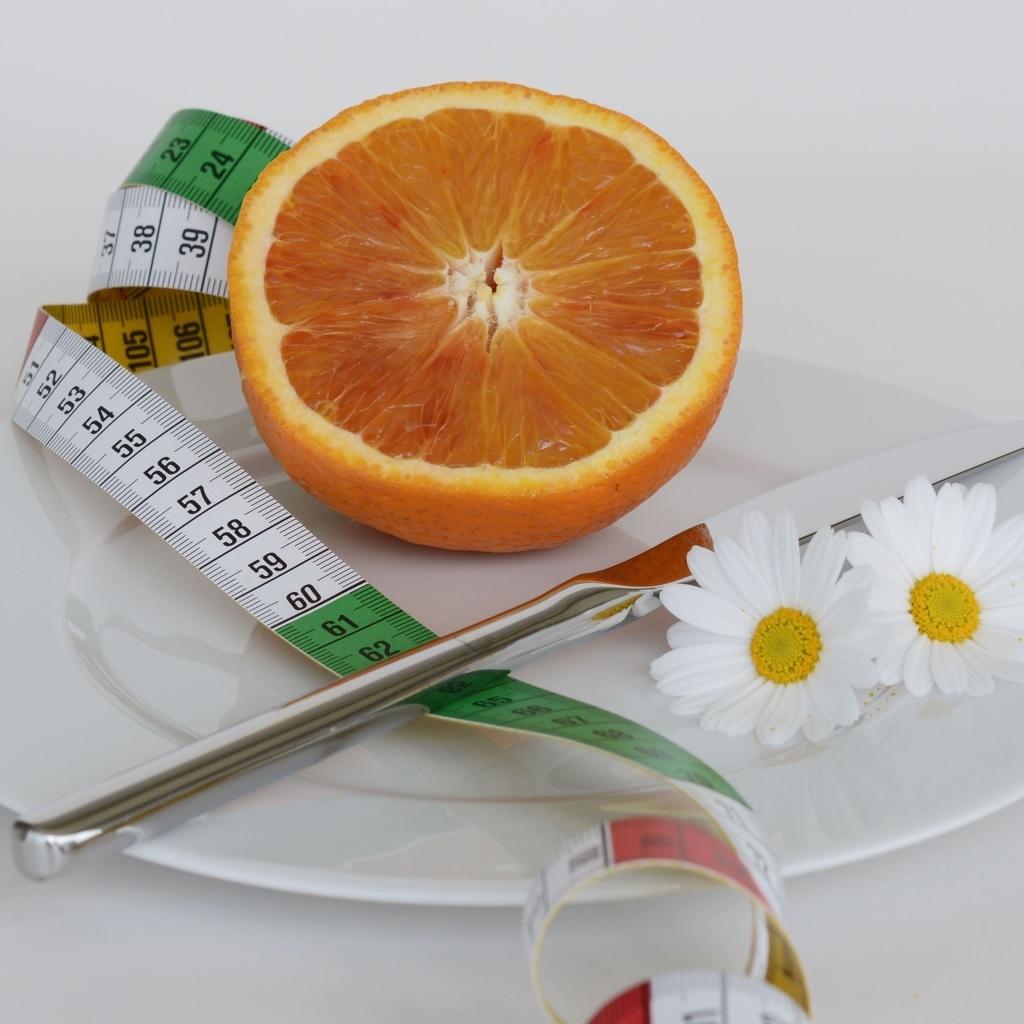 Половина апельсина на тарелке с сантиметром