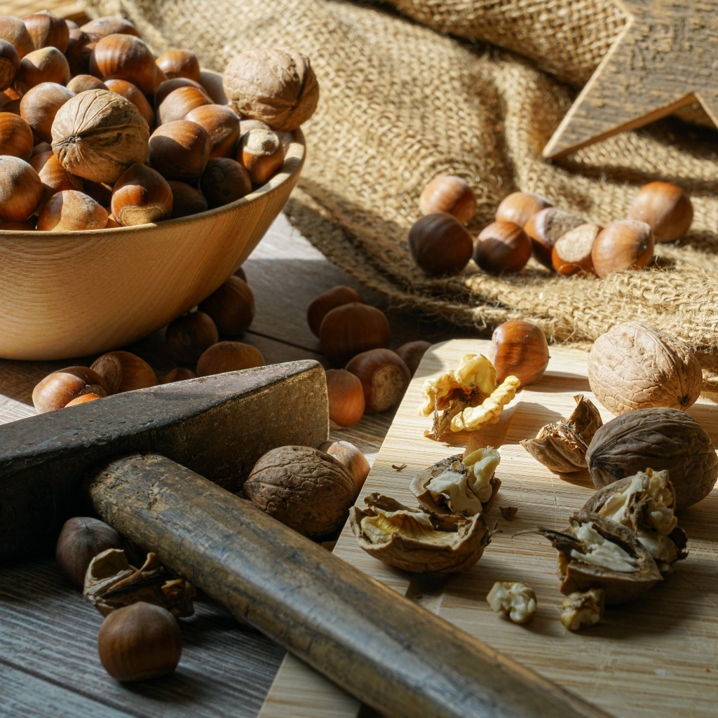 Фундук и грецкие орехи на столе с молотком