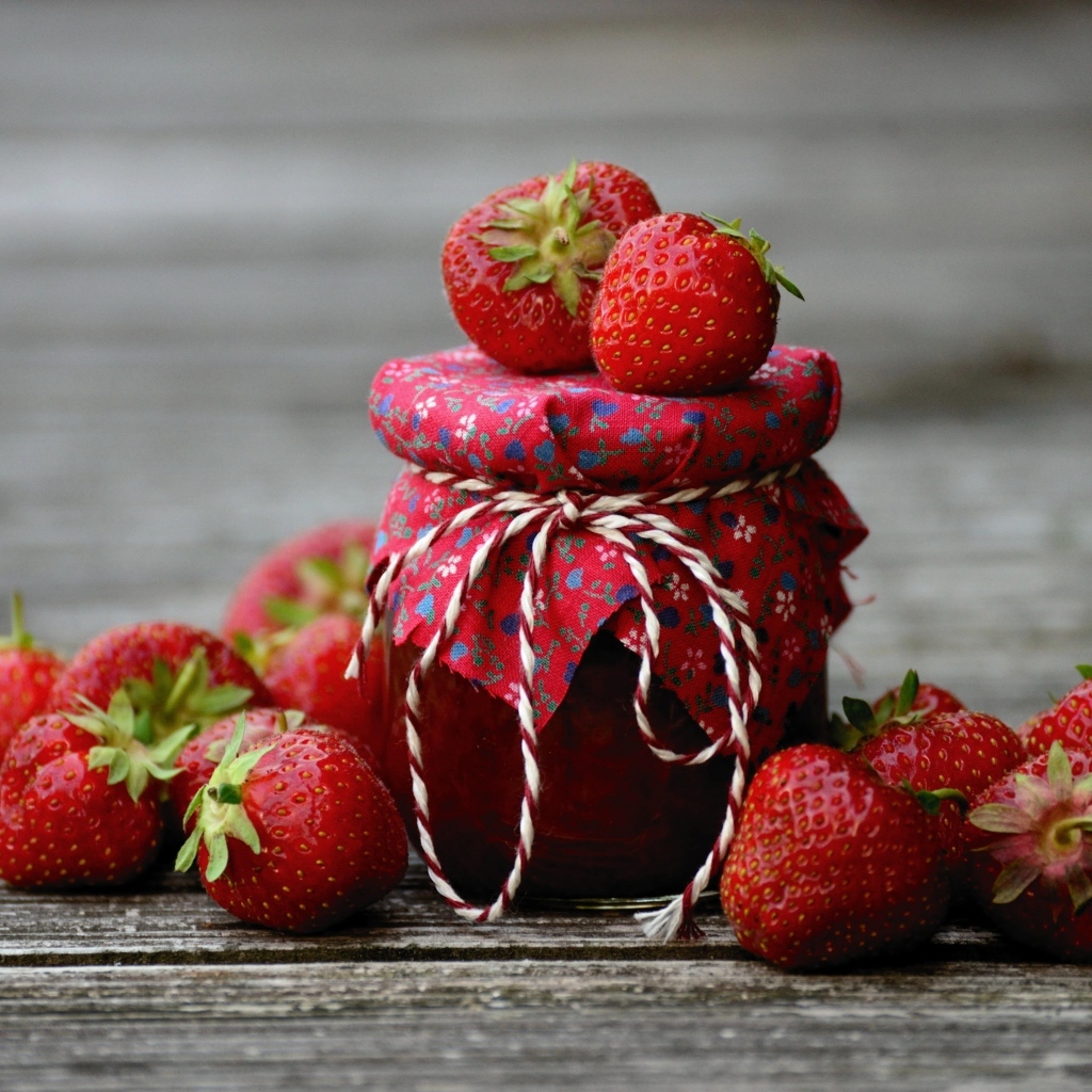 Банка джема на столе со свежими ароматными ягодами клубники