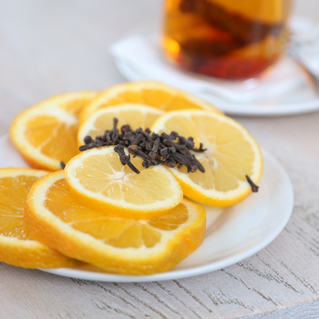 Лимон и апельсин с гвоздикой на тарелке