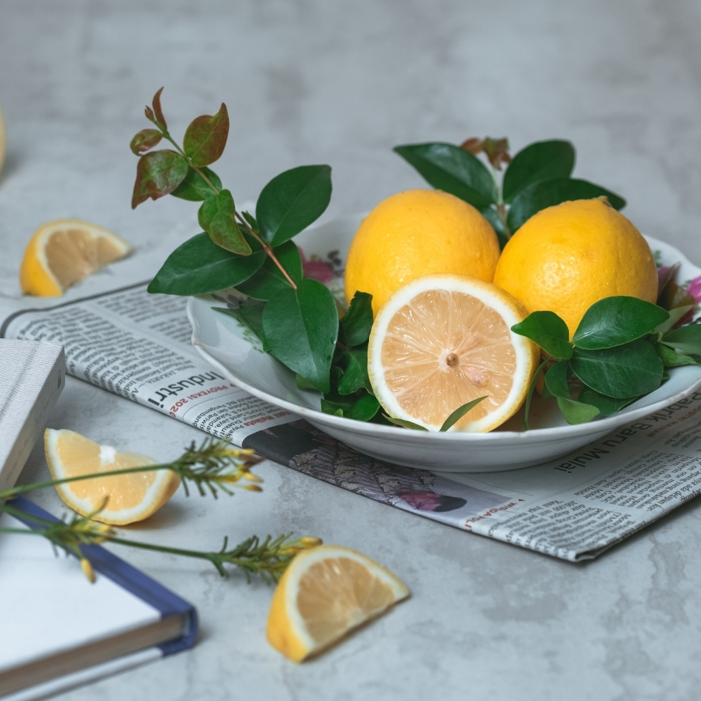 Лимоны на тарелке с зелеными листьями