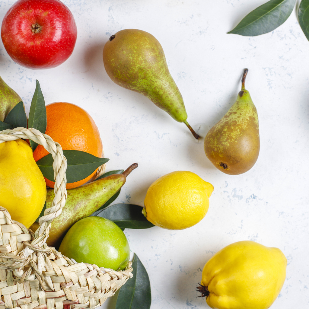 Груши, яблоки и апельсины с сумкой на столе