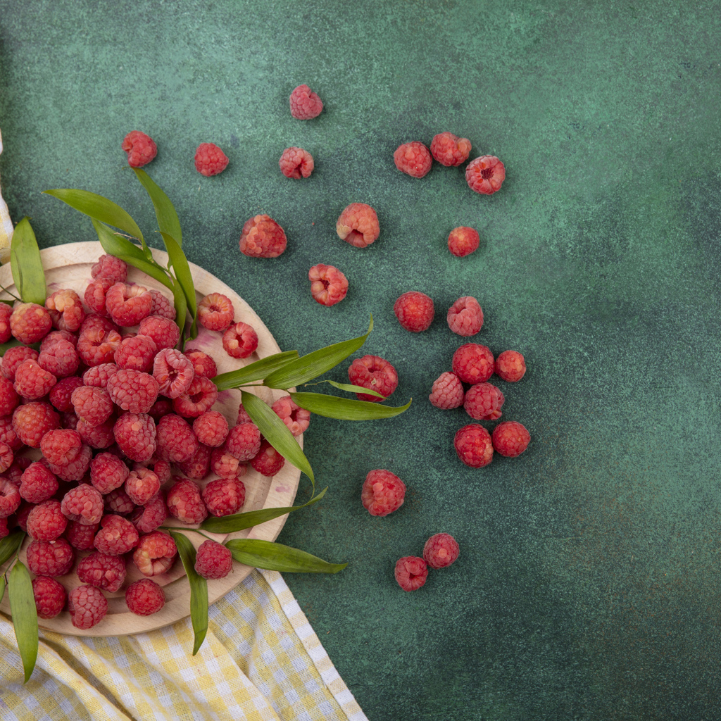 Красная малина с зеленой листвой на столе