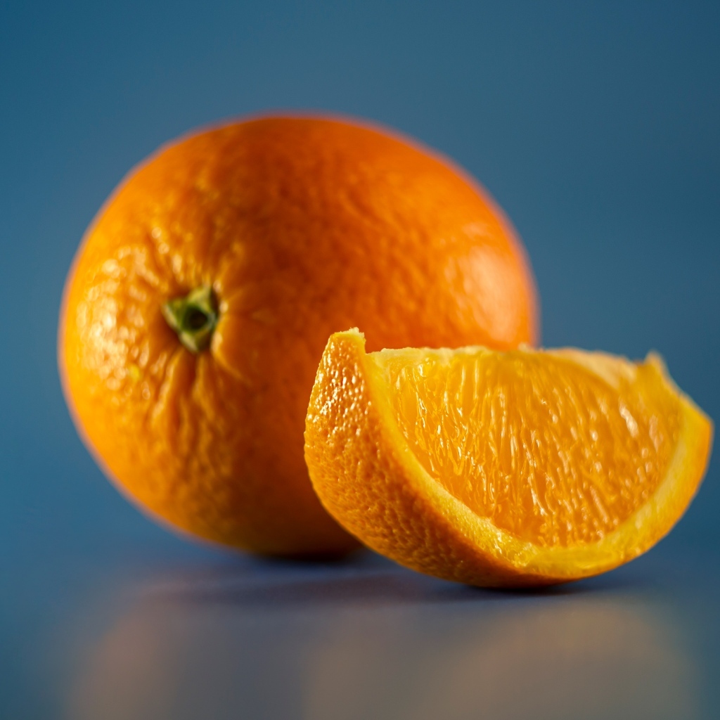 Спелый оранжевый апельсин на голубом фоне