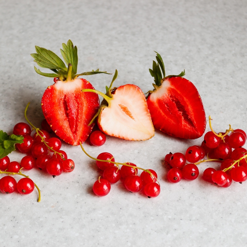 Ягоды клубники с красной смородиной на сером столе