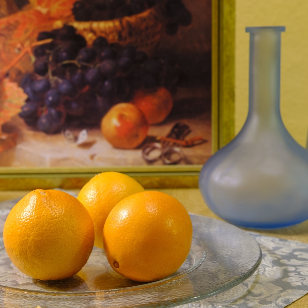 Три апельсина с вазами на столе