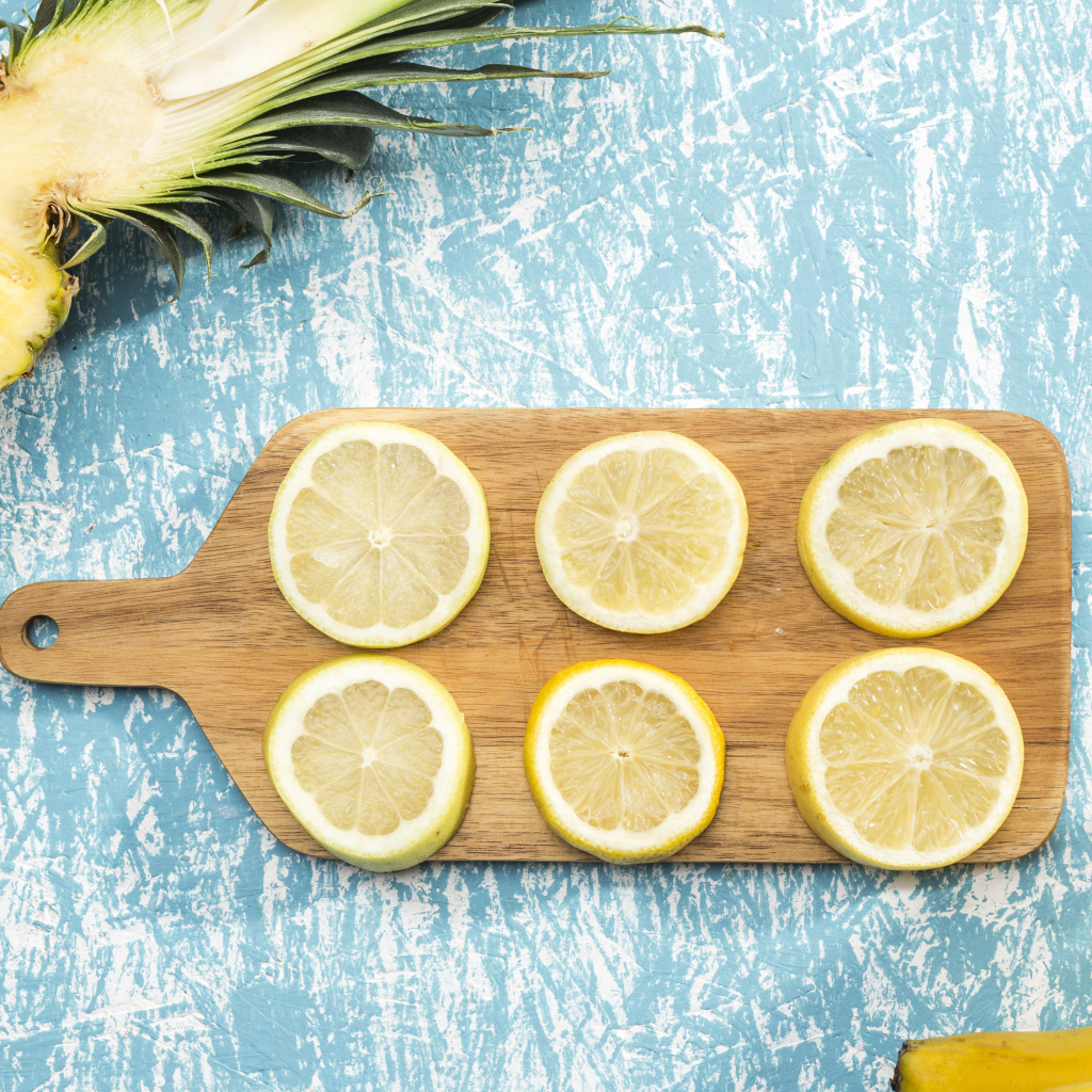 Деревянная доска с лимоном на столе с ананасом