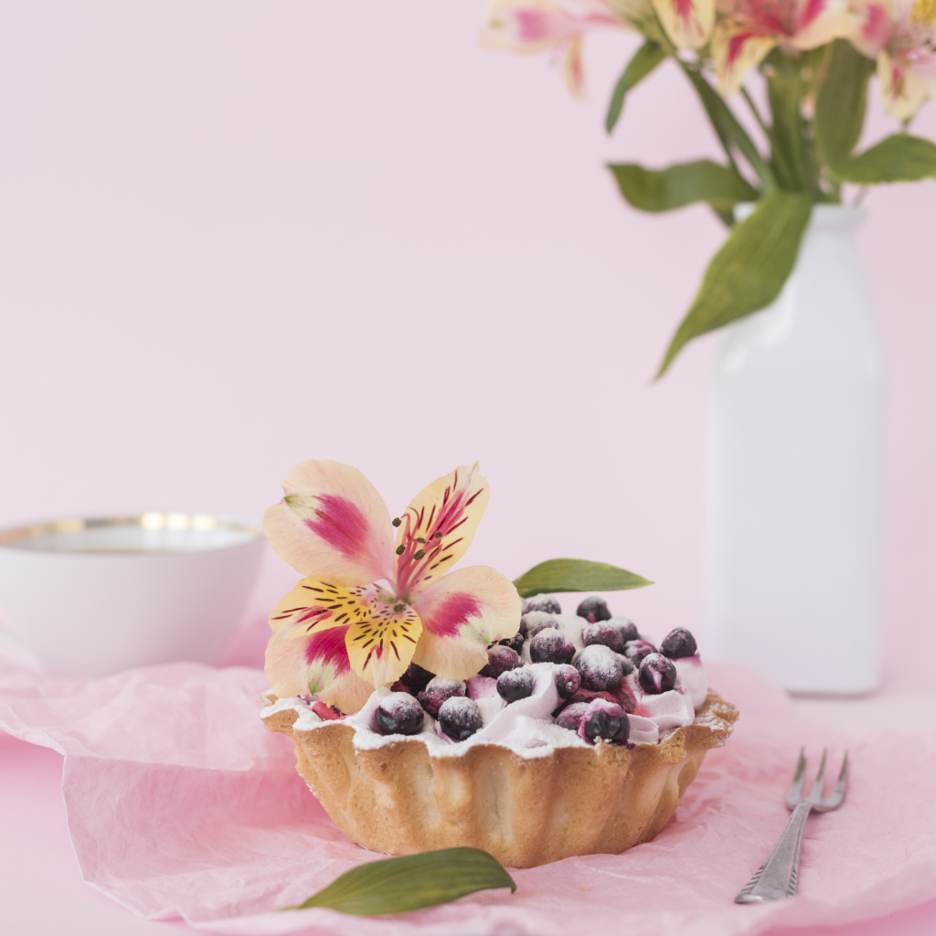Черничное пирожное с цветами альстромерии на розовом фоне
