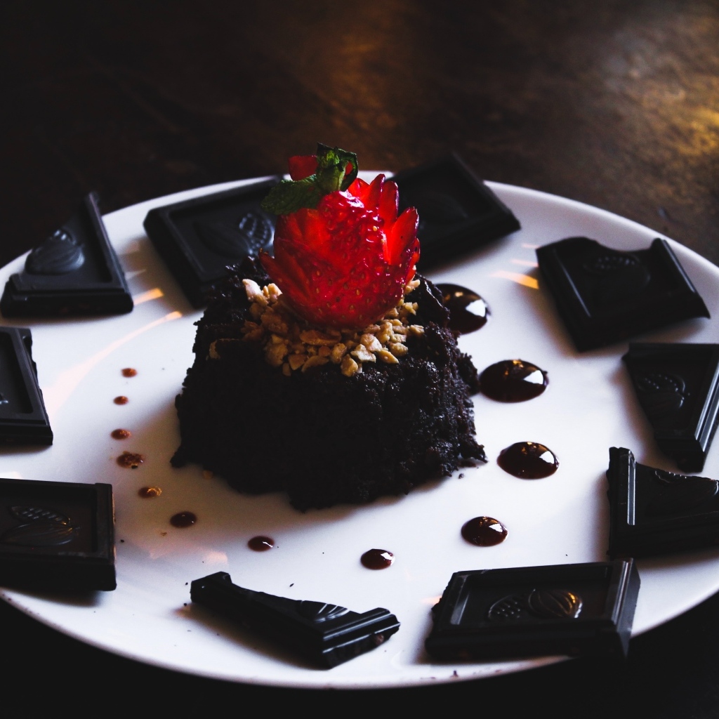 Десерт брауни на большой белой тарелке с шоколадом