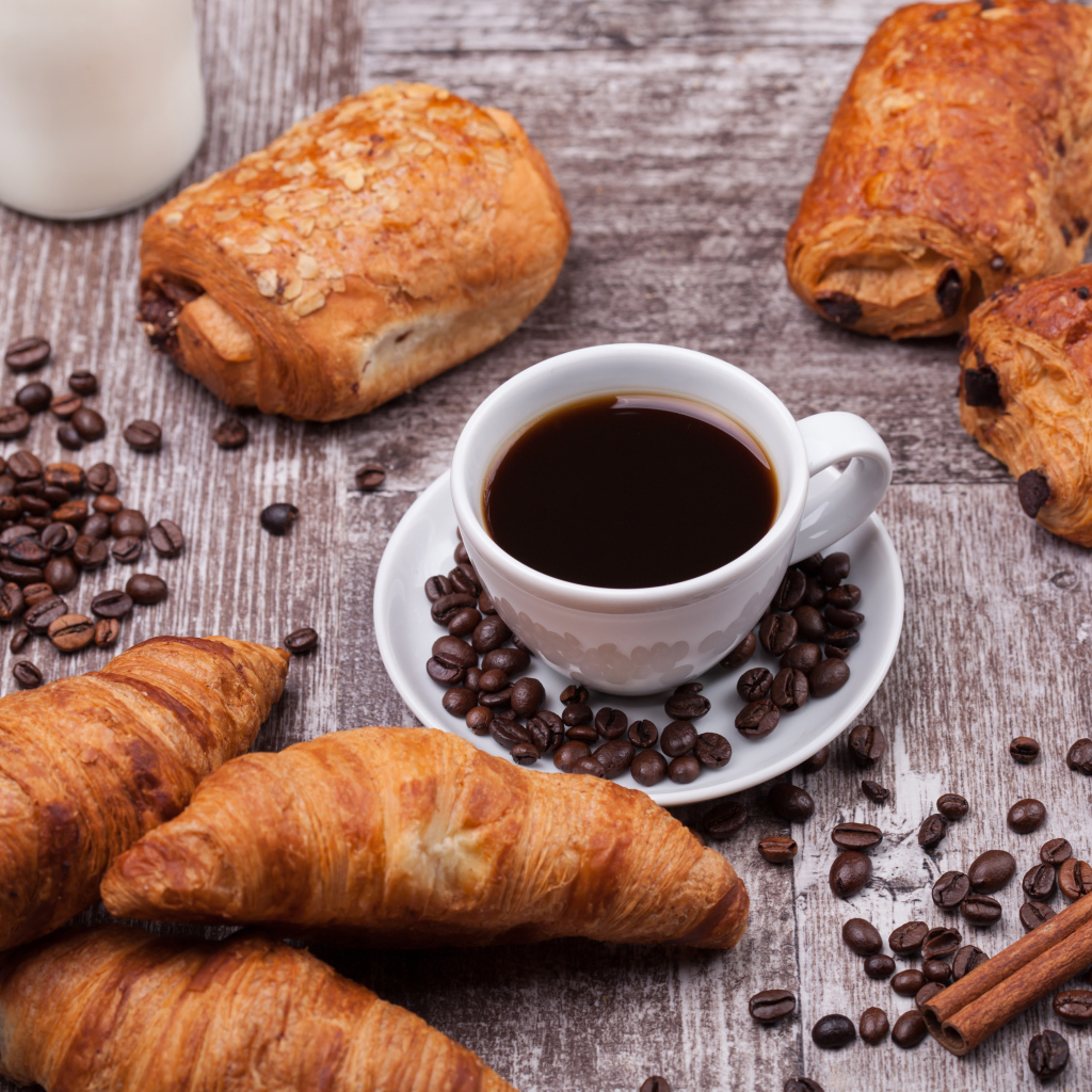 Кофе на столе с круассанами и зернами
