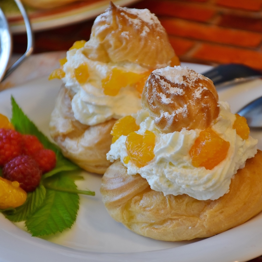 Заварное печенье со взбитыми сливками на тарелке с ягодами