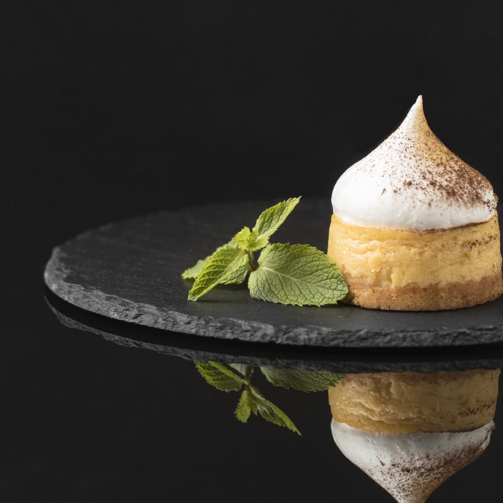 Десерт с кремом и листьями мяты на черном фоне
