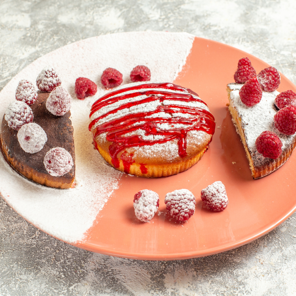 Десерт с ягодами малины и сахарной пудрой на большой тарелке