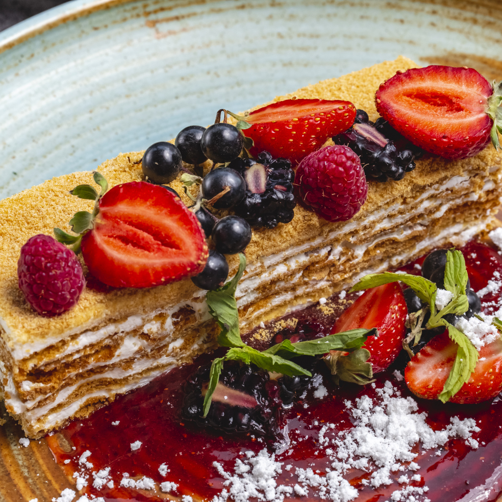 Большой кусок медового торта с ягодами