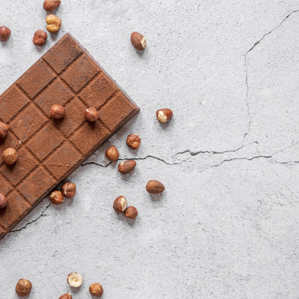 Молочная шоколадка с орехами на сером столе