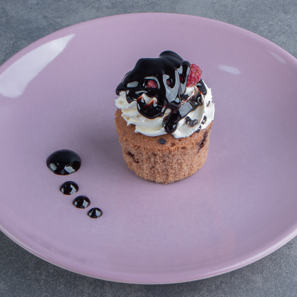 Маффин с шоколадным топпингом на большой тарелке