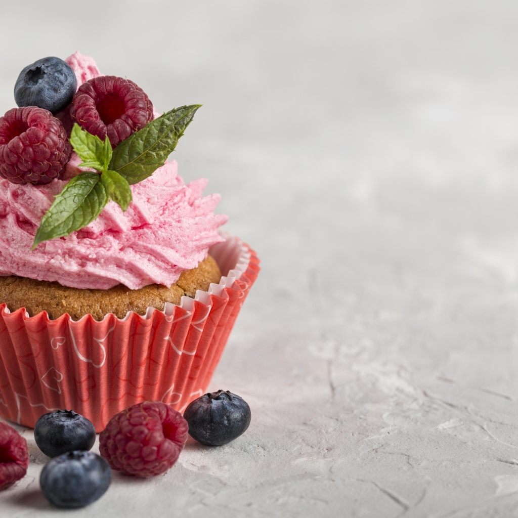 Маффин с розовым кремом и ягодами на столе