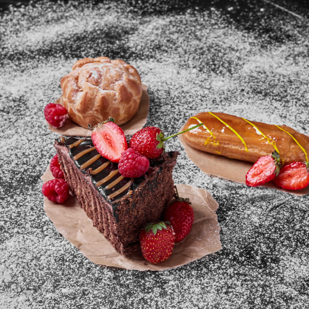 Кусок торта с ягодами на столе с эклером