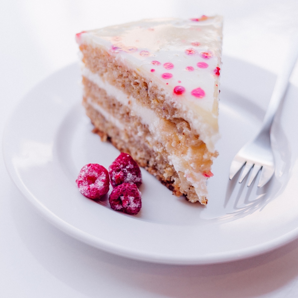 Кусок торта с замороженной малиной на белой тарелке