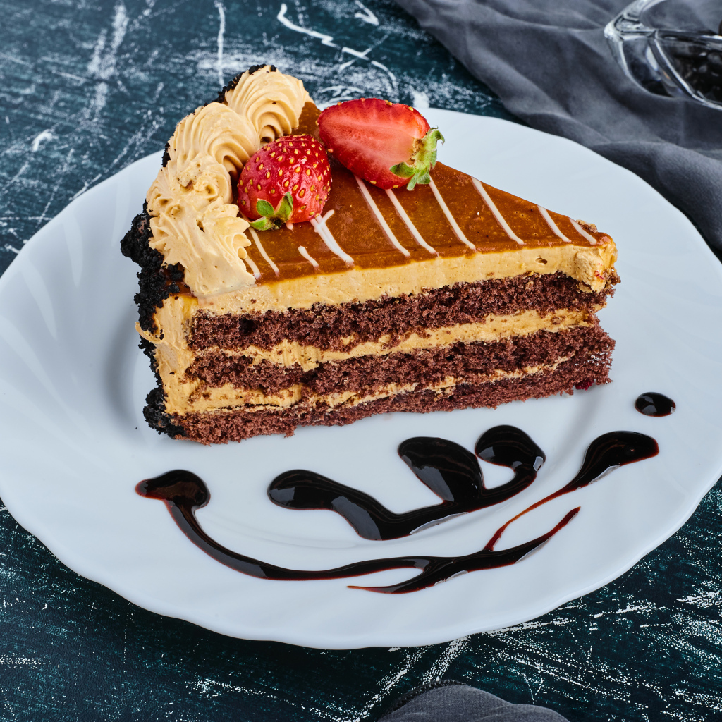 Кусок торта с клубникой на большой белой тарелке