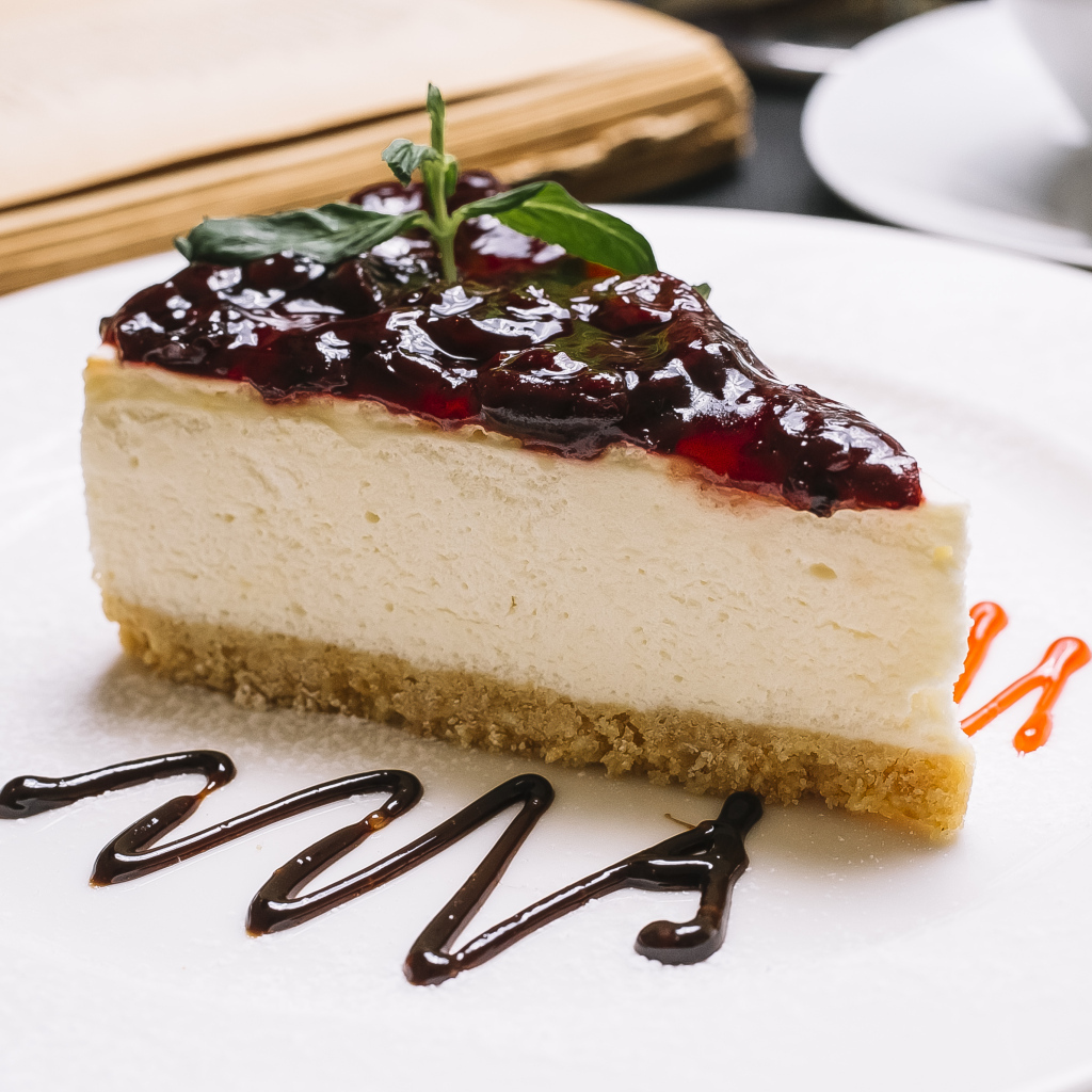 Кусок чизкейка с джемом на белой тарелке