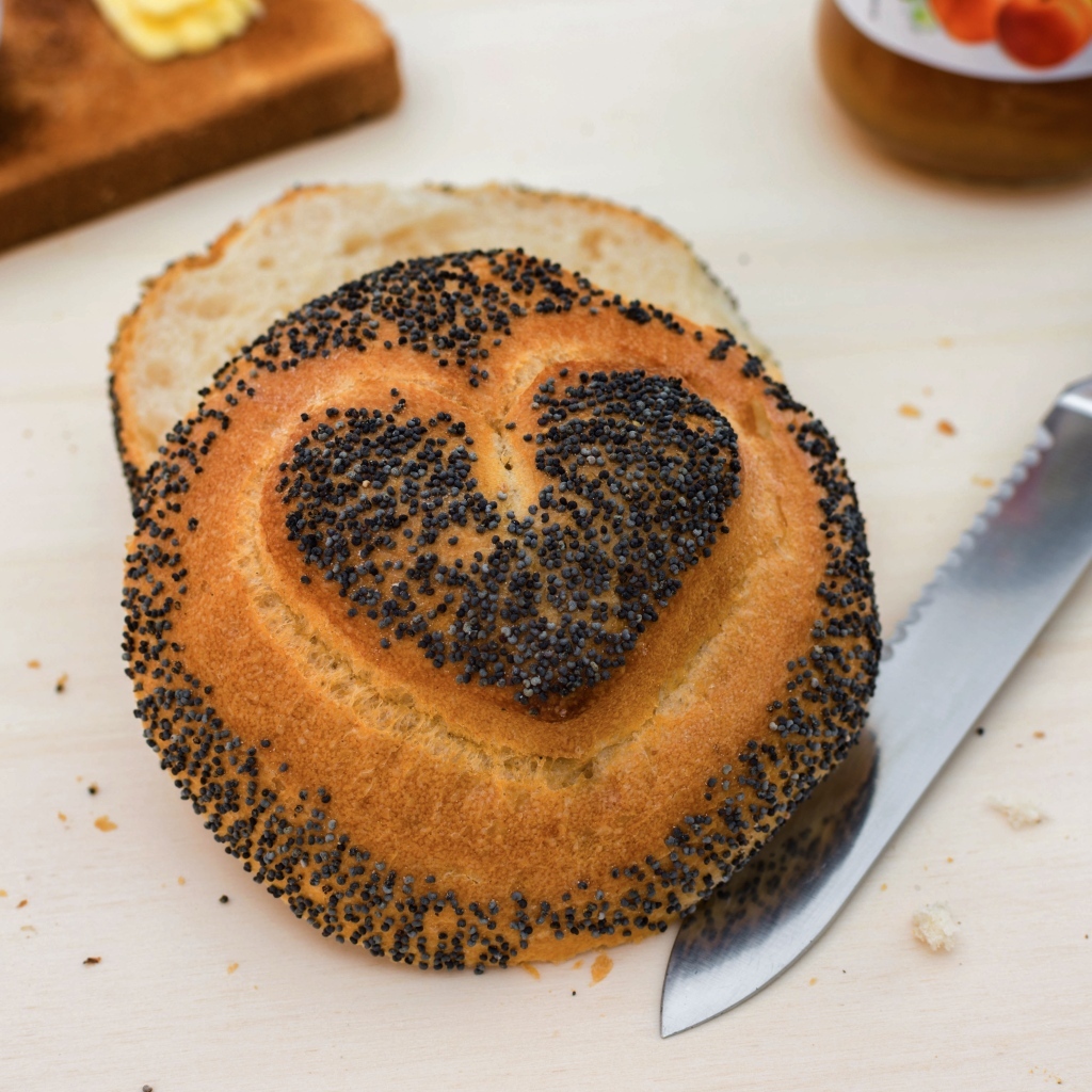 Булочка с маком с нарисованным сердцем на столе