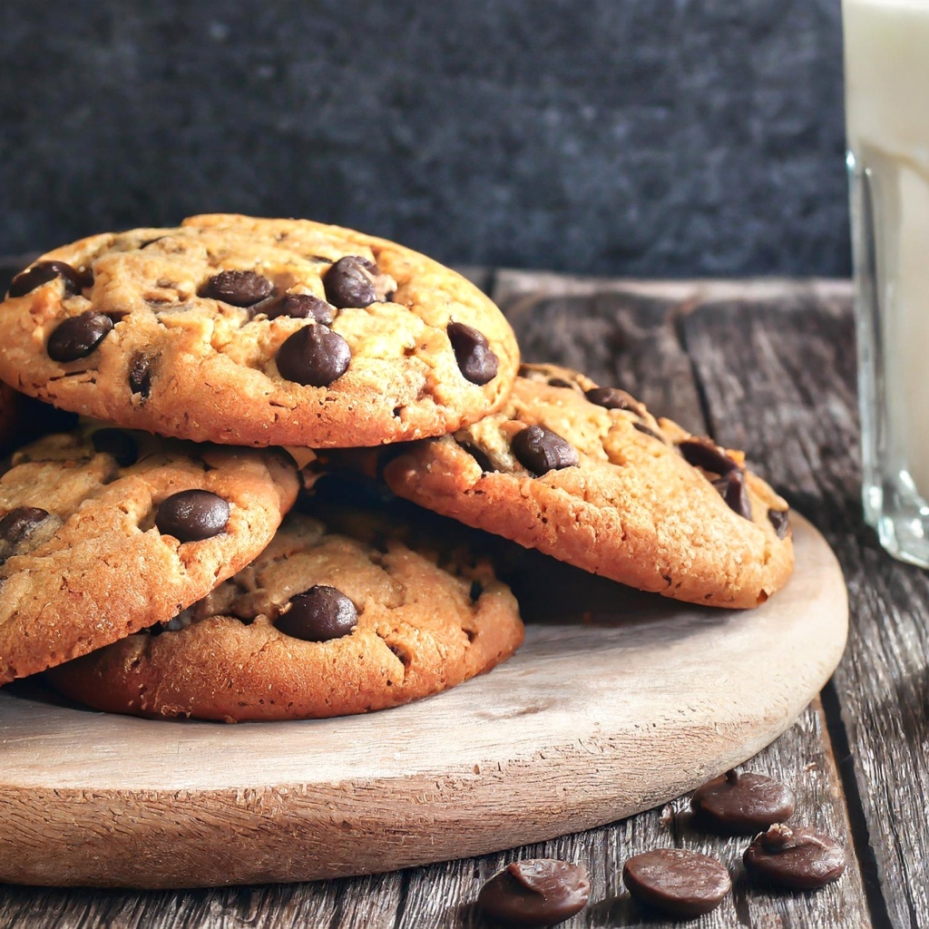 Круглое печенье с шоколадом на столе со стаканом молока