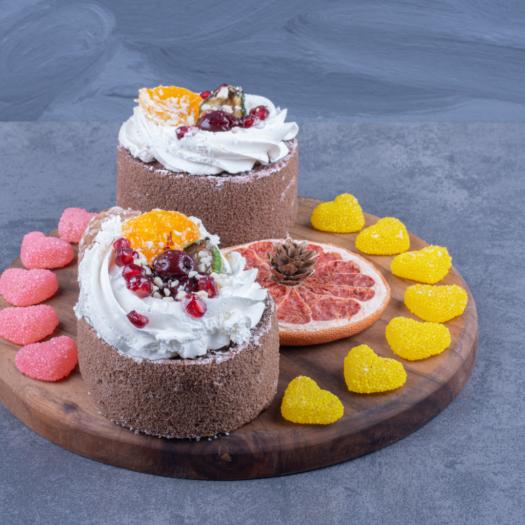 Два пирожных на деревянной доске с мармеладными конфетами