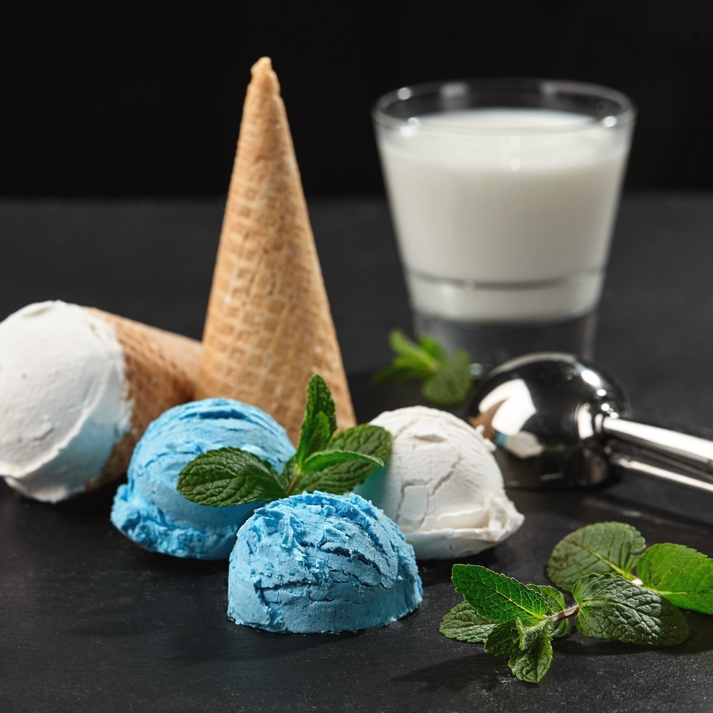 Вафельный рожок с шариками мороженого, мятой и молоком на столе