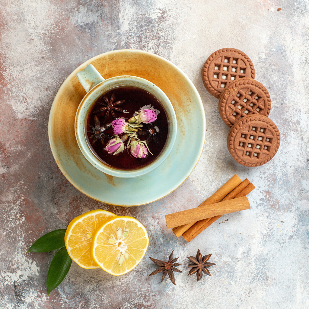 Чашка ароматного чая на столе с лимоном, печеньем и пряностями