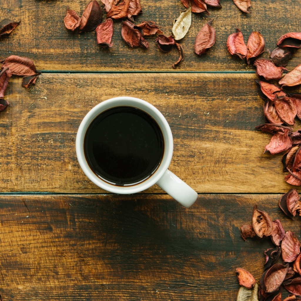 Чашка кофе с опавшими листьями на деревянном столе