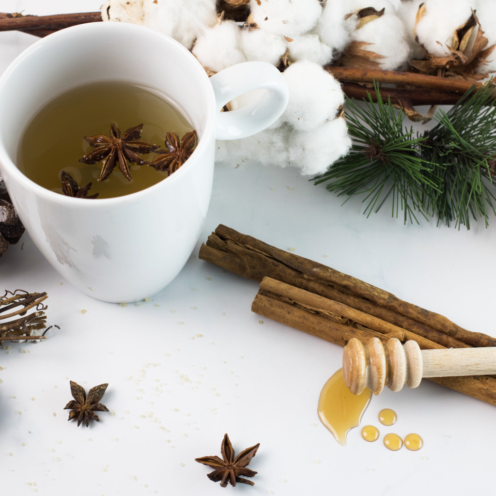 Чашка чая со специями на столе с хлопком и шишками