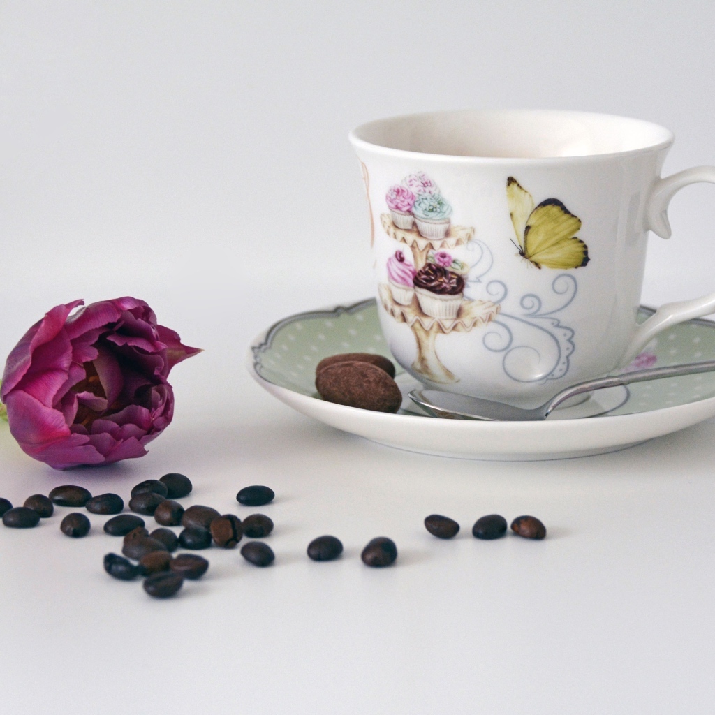 Чашка на столе с кофейными зернами и тюльпаном