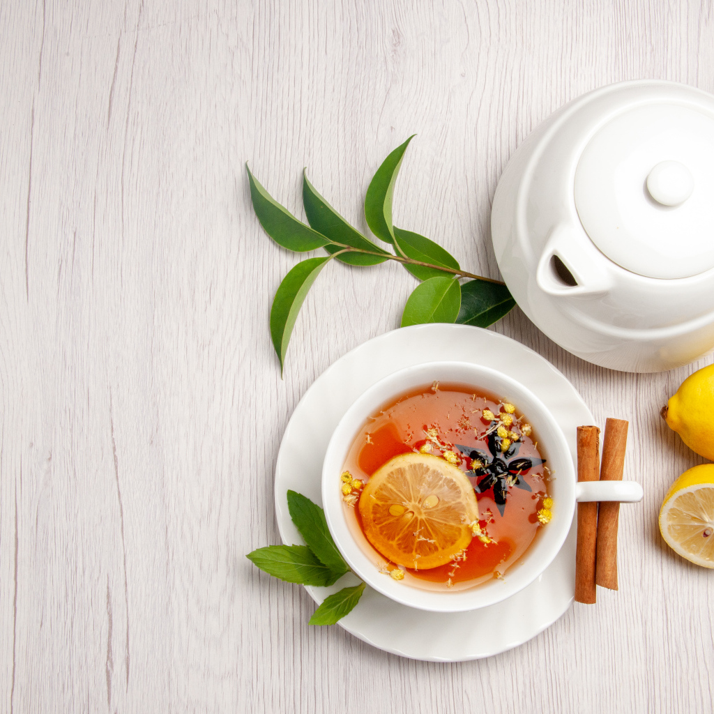 Вкусный чай в белой чашке на столе с лимоном и чайником
