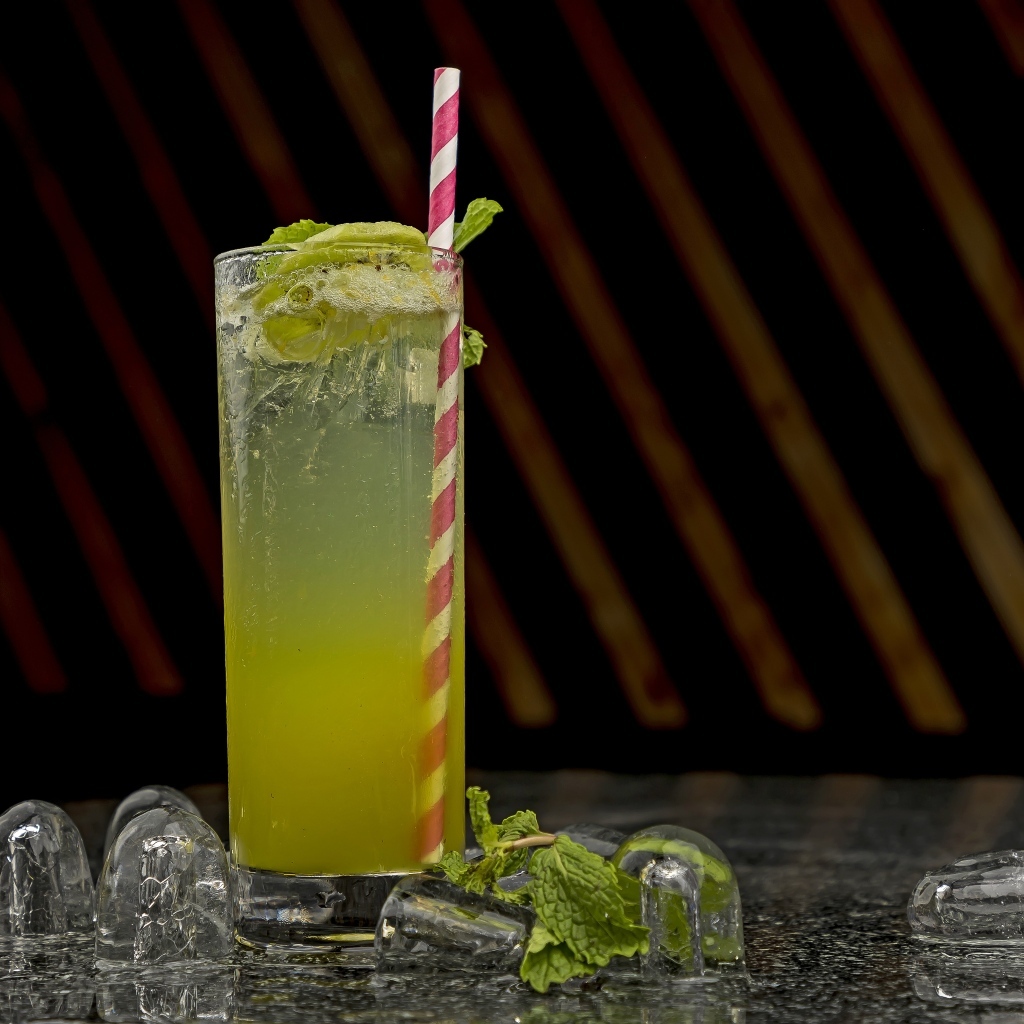 Зеленый коктейль мохито в высоком стакане со льдом