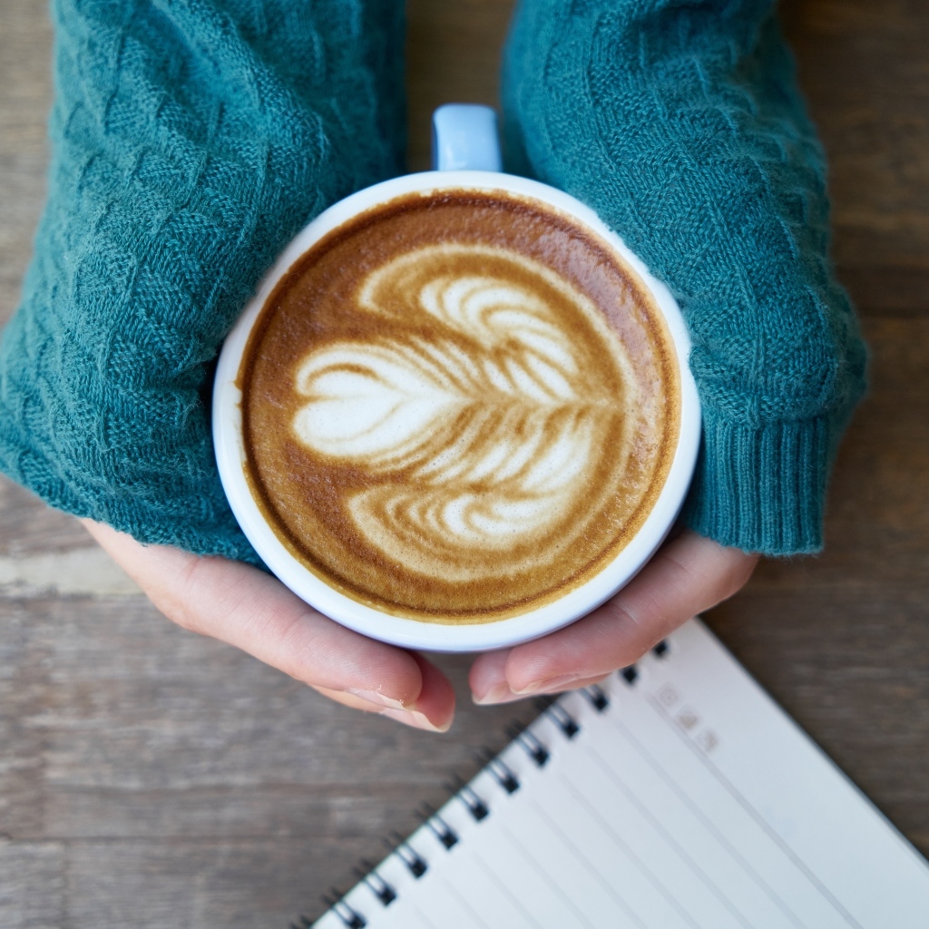 Горячая чашка кофе на столе в руках девушки