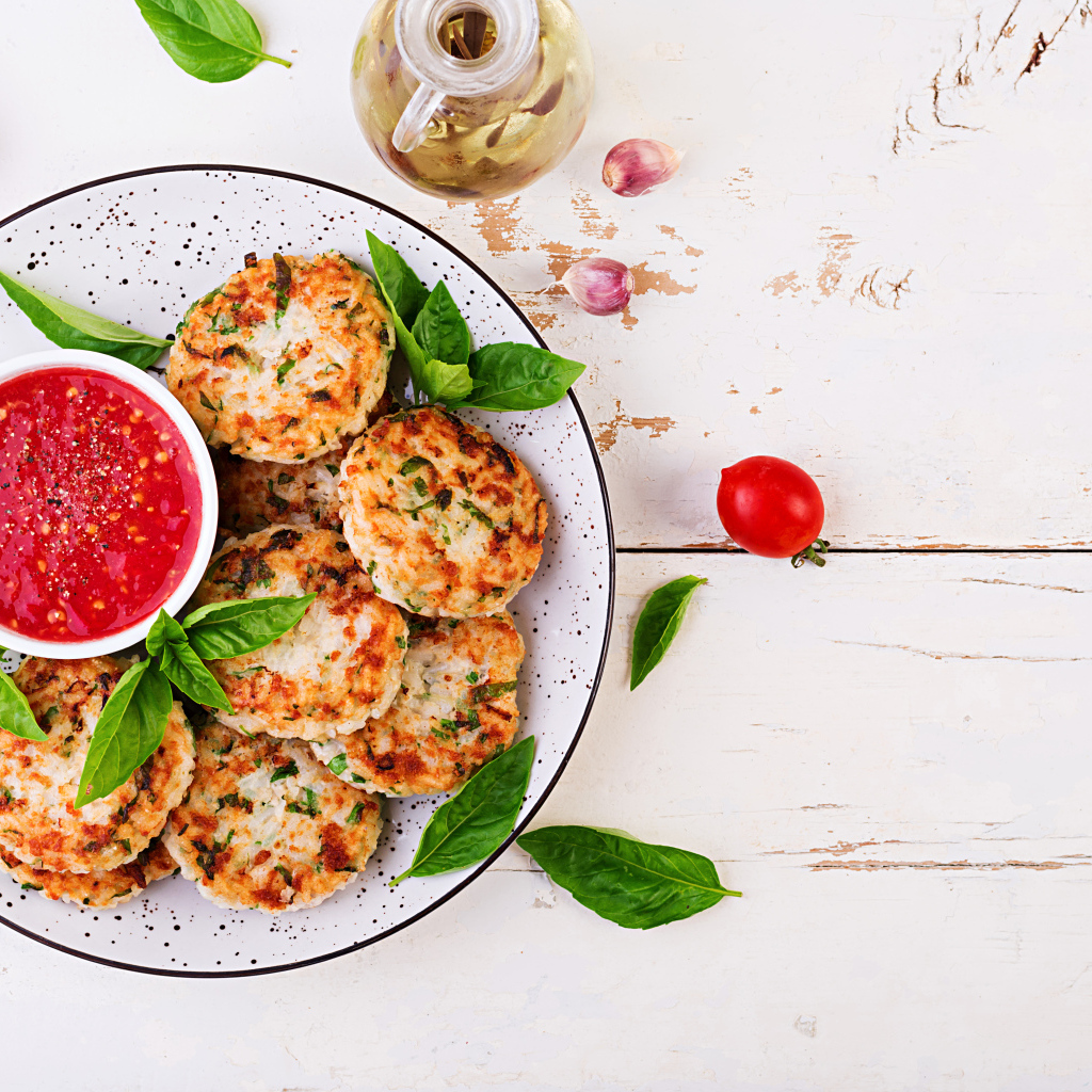 Куриные котлеты на большой белой тарелке  с соусом