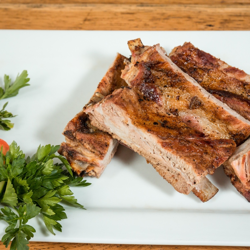 Свиные ребра на тарелке с овощами и зеленью