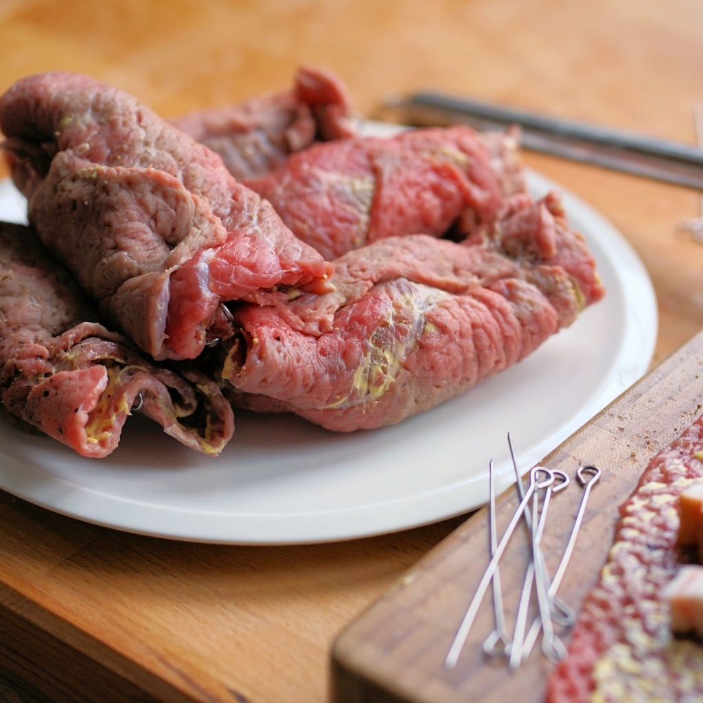 Рулетики из свинины на большой белой тарелке