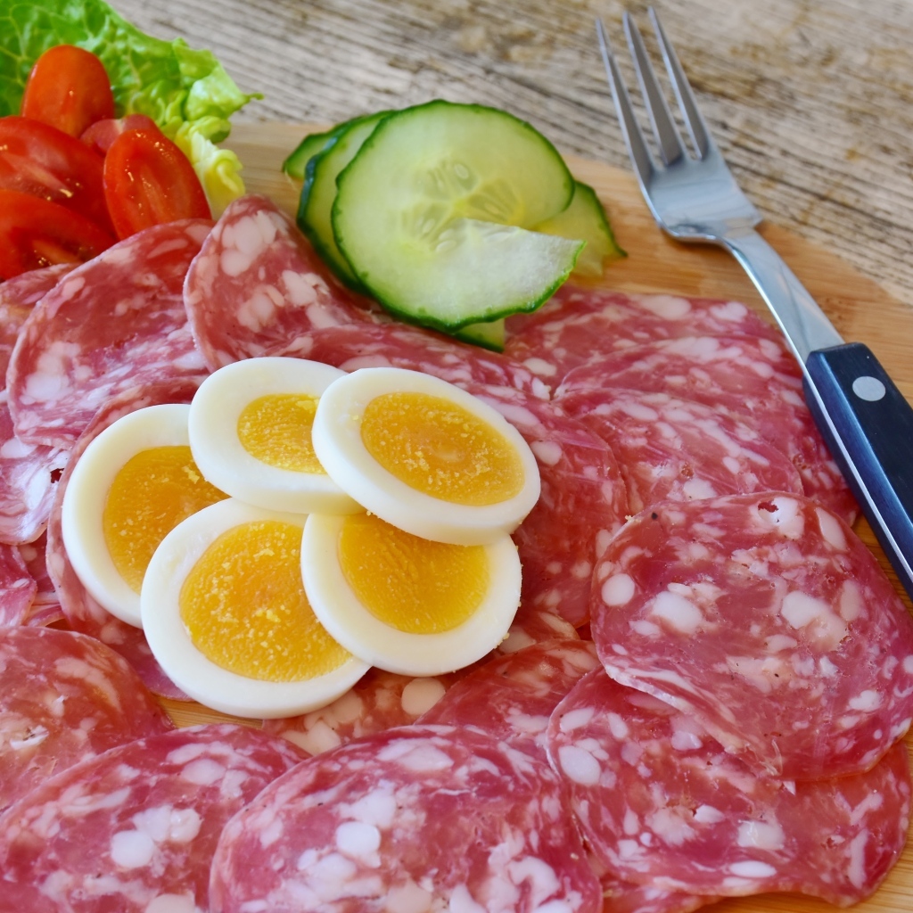 Колбаса салями на доске с вареными яйцами и овощами