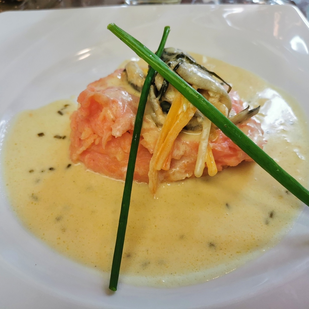 Красная рыба с соусом на тарелке с зеленым луком