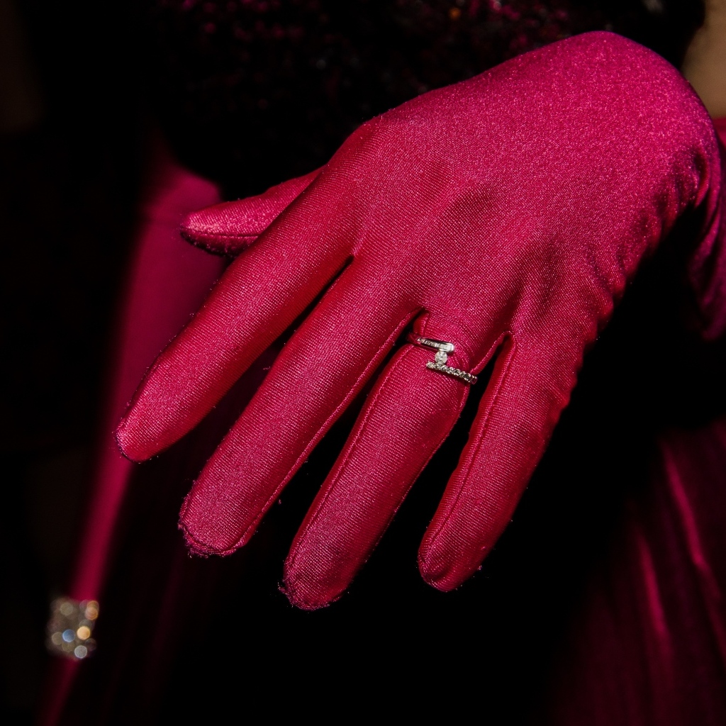 Женская рука с красной перчаткой и кольцом