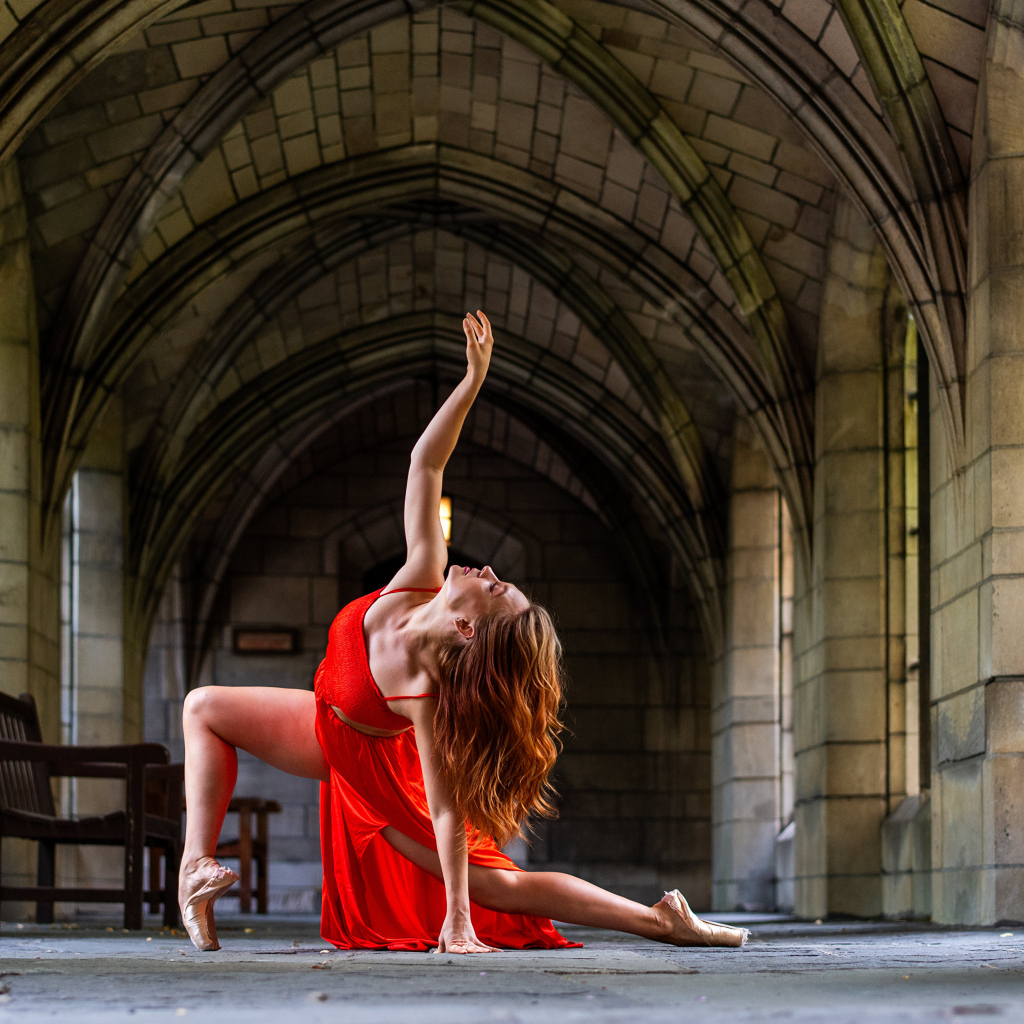 Девушка в красном наряде танцует в здании