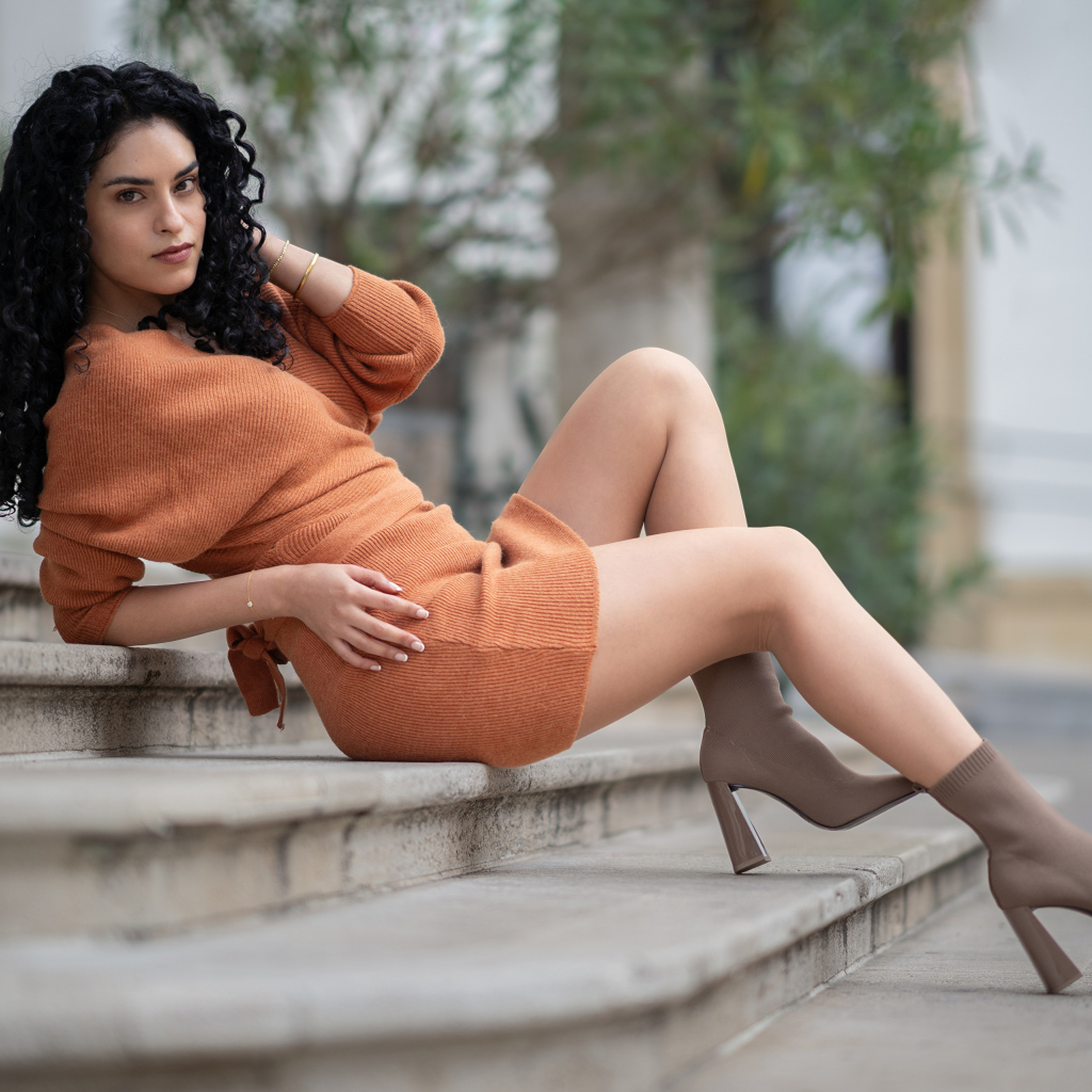 Девушка в теплом платье лежит на ступеньках