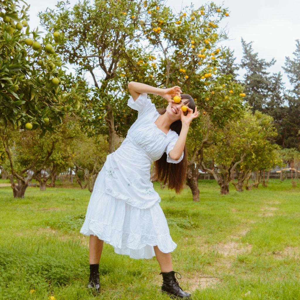 Девушка в белом платье закрыла глаза лимонами